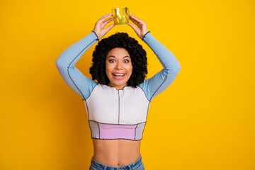 Smiling young woman in a vibrant outfit holding a crown, showcasing concept of joy, style, self-confidence, and celebration