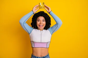 Fotobehang Muziek Smiling young woman in a vibrant outfit holding a crown, showcasing concept of joy, style, self-confidence, and celebration  © deagreez