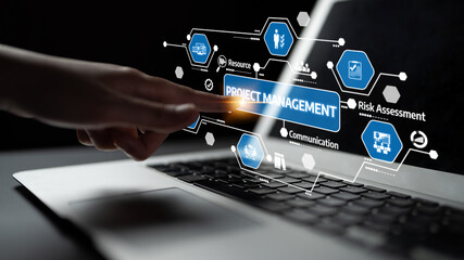A close-up of a hand using a laptop with a digital project management interface. The image captures...