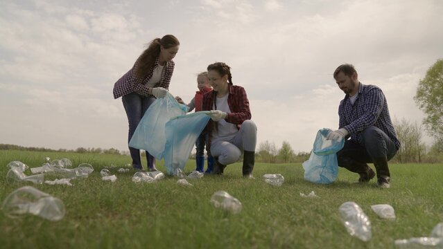 A small child with his parents collects trash in a park recreation area, group cleaning of the territory, ecology of cleanliness, collection of plastic bottles, waste, teamwork, happy family and kid.