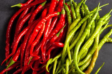 Top view of red and green chili peppers placed side by side on a dark background. Fresh, spicy vegetables perfect for culinary, food, and agricultural concepts.