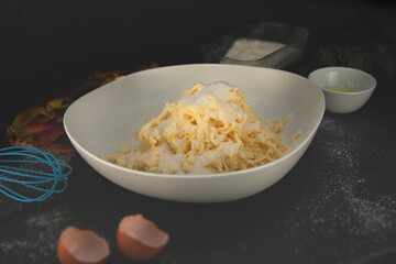 Grated butter mixed into flour with eggs, oil and autumn leaves around — cozy homemade baking preparation in a rustic fall kitchen.