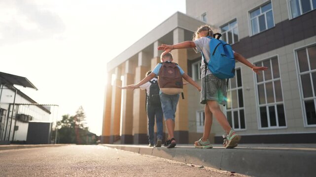 Children walking to school campus on sidewalk by modern building with backpack and sunlight, child friend and education vibe as kids walk together past school entrance under warm afternoon light