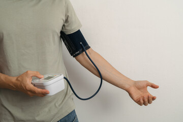 Man measuring blood pressure at home with digital monitor (horizontal)
