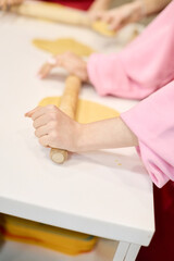 Hands rolling dough with wooden rolling pin