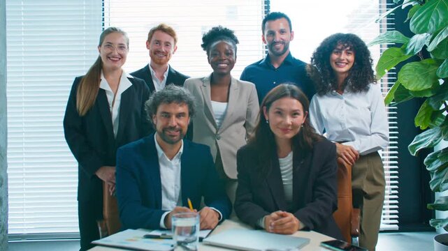 Group of diverse businesspeople posing together in office. Smiling colleagues looking directly at camera showing unity and confidence. Team portrait after successful meeting or project completion.