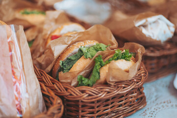 Delicious homemade sandwiches wrapped in paper, served in charming woven baskets at a cozy outdoor...