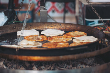 Delicious treats sizzle on a hot pan at a vibrant street market during sunny afternoon hours