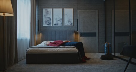 Handsome Mature Man Checks Into Modern Hotel Room. Businessman Takes Off Jacket and Lies Down on...