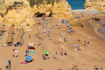 Camilo Beach (Praia do Camilo) people were sunbathing on the beach and swimming in the ocean. Ponta da Piedade near Lagos in Algarve, Portugal.