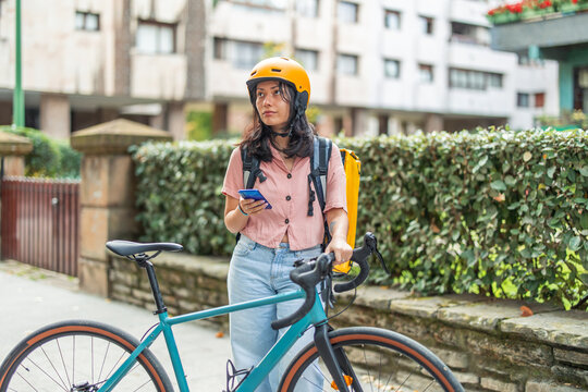 Asian delivery woman checking smartphone app on bike