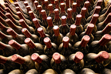 Obraz premium Bottles of wine lined up in a dimly lit cellar at wine cellar