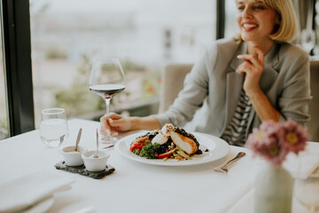 Enjoying a gourmet meal with wine in a cozy restaurant by the water during a sunny afternoon
