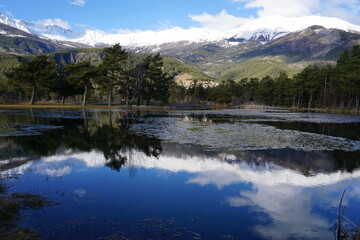 mountain landscape with small lake and mirror reflection of the peaks in southern alps, france