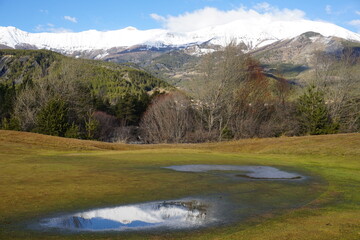 mountain landscape with water puddle and mirror reflection of the peaks in southern alps, france