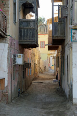 Narrow, dirty dirt road between crumbling multi-story buildings