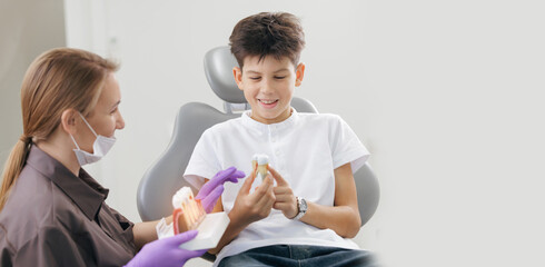 Obraz premium Asian female dentist educates young caucasian male patient on dental health