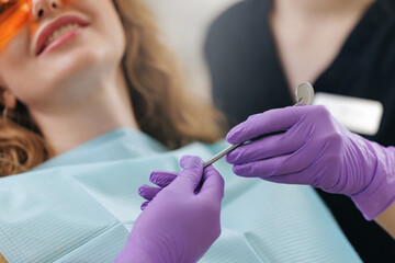 Assistant hands dentist probe and mirror on background Caucasian woman getting dental checkup