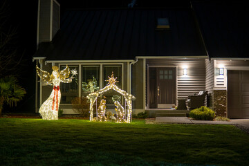 Nativity scene with luminous figurines of angel, Jesus, Mary, Joseph in front yard. Nativity scene...