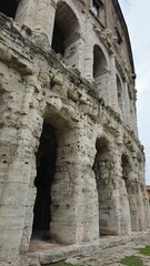 Naklejka premium Rome, Italy - 11 January 2025. Ground-level arches of the Theatre of Marcellus show aged travertine pillars beneath rising tiers of Roman arcades and brick windows.