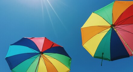 Colorful rainbow beach umbrellas seen from below against sunny blue sky. Summer vacation and travel concept with copy space