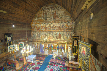 Maramures, Romania - Aug 13, 2025: historic Saint Nicholas wooden church in Budesti. Maramures. Romania with traditional Orthodox frescoes. Ancient wooden beams and rustic ecclesiastical decor