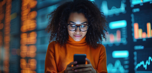 Young woman glasses orange sweater holding smartphone. She looks at screen data graphs background. Analyzing finance charts using mobile tech. Browsing info, global net.