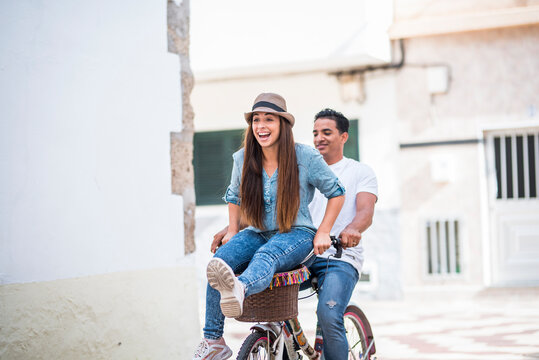Young mixed-ethnicity couple enjoying time together outdoors during a relaxed day out, walking, laughing and sharing a romantic moment; youthful love, connection, leisure lifestyle and authentic emoti - Powered by Adobe