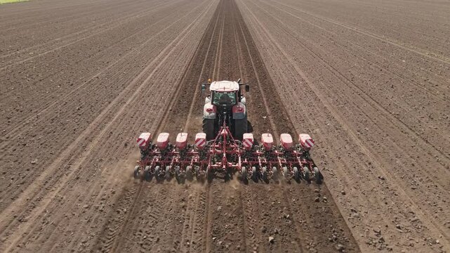 Agricultural tractor plowing soil with precision, showcasing planting equipment in action, camera follows movement across the field