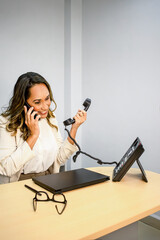 Happy Employee Multitasking with Smartphone and Office Desk Phone