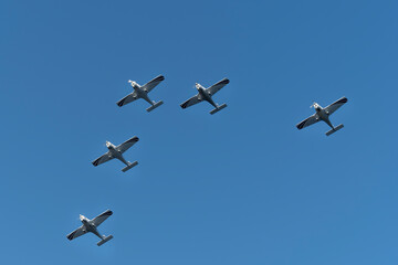 Group of aircraft planes in flight during airshow. Jets flying in the air. Airborne sport in thr sky with airplanes with blue background.