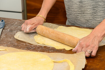 Woman rolling Napoleon cake layers on home kitchen counter