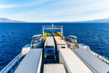 naval transport cargo ferry ship transporting wagon trucks to a destination port to supply trade goods to commercial sea port throuth sea and ocean