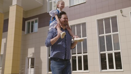 child student with school backpack rides on his father shoulders, dad cheerfully runs with his daughter kid to school, happy childhood laughing girl with bag, children runs with parent, happy family.