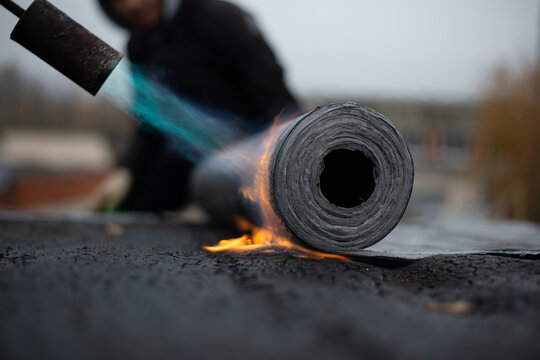 laying of a new bitumen roof on the roof. bitumen roll melting and adhesion, to protect the leakage. High quality photo