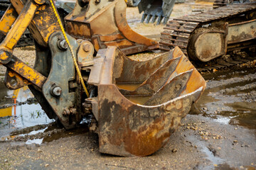 Old excavator bucket with visible rust and dirt representing heavy construction work, industrial machinery maintenance and earthmoving operations at outdoor building site