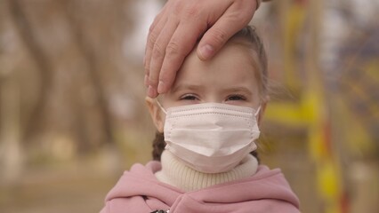 little girl smiles in medical mask her face, time coronavirus pandemic, protect healthy body from viral infection covid-19, child walks on playground, children lifestyle, rules for being public places