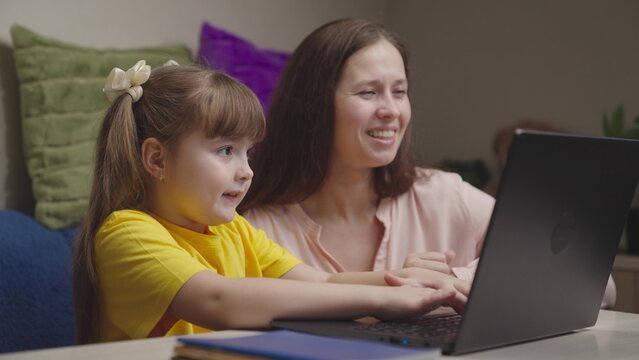 cheerful happy mom with child doing homework laptop. american education online. teamwork. happy family. child kid daughter hugs parent mother. together to win going to success. maternal care love kid. - Powered by Adobe