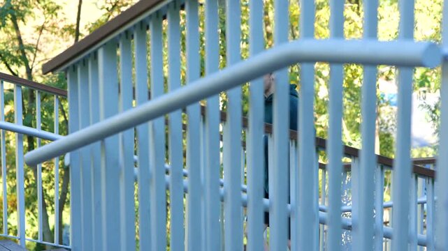 Young Caucasian man running up stairs in park on summer sunny day