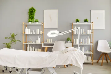Fotobehang Badkamer Clean and bright spa treatment room with an empty massage bed, towel, magnifying lamp, shelves of cosmetic products. The image represents a modern, professional, and relaxing beauty care environment.  © Studio Romantic