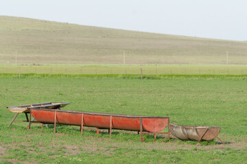 Empty animal feeding troughs standing in rural pasture field