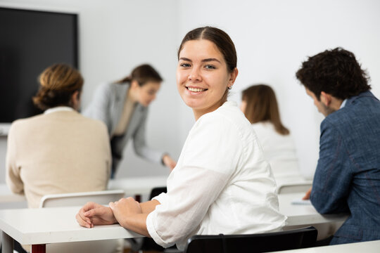 Cheerful woman turning around and looking at camera during advanced training course in auditorium