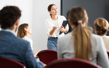 Young female teacher giving lecture to group of student