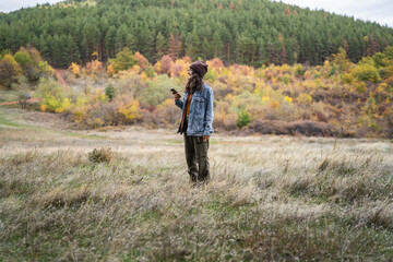 Woman enjoying autumn nature holding mobile phone in field