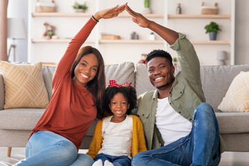 A joyful family sits on the floor of their cozy living room. They are playing a game with their...