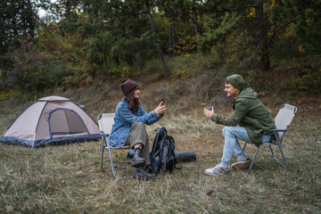 Couple camping in forest experiencing digital detox and connecting