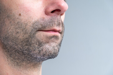 Obraz premium Close-up side profile man’s face with short stubble and early gray hairs, Facial hair detail, Natural beauty in aging, Signs maturity, highlighting facial texture and natural aging, neutral background