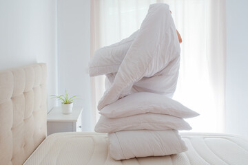 Woman changing winter bedding with duvets and pillows on bed, seasonal home care and apartment rental preparation