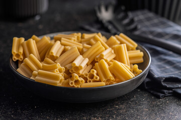 Cinque buchi. Uncooked italian pasta in bowl on black table.