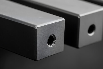 Obraz premium Close-up of a square metal bars with centered holes, showcasing industrial design and precision engineering. The monochromatic palette adds a touch of sophistication.